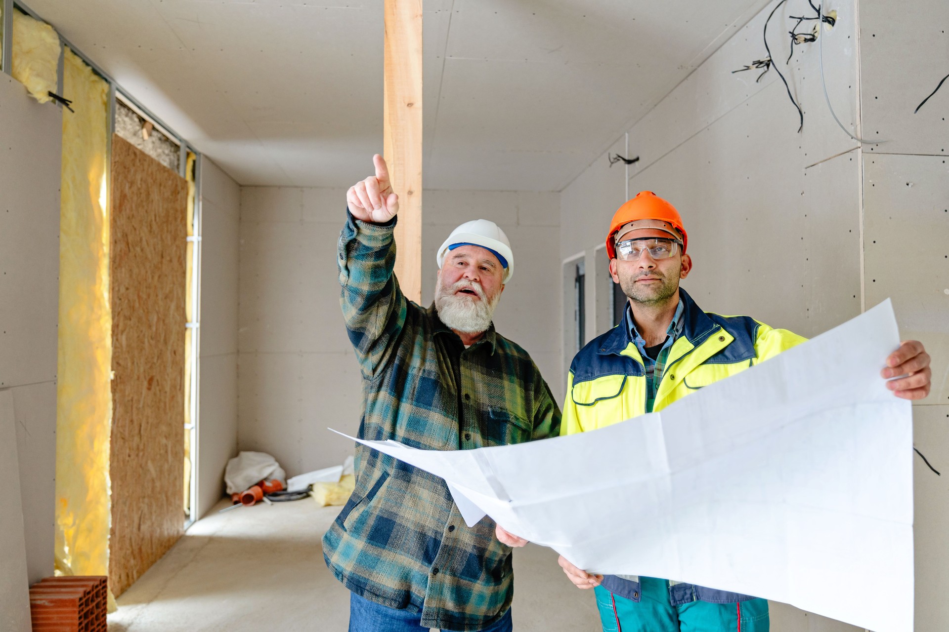 Home owner and construction worker analyzing blueprints during apartment renovation